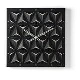 Orologio da parete Wallpape nero/avorio dal carattere moderno e originale, con struttura scatolare in ferro e superficie decorata con tagli ispirati all'origami. Vista frontale.