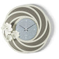 Orologio da parete Tahiti dal design floreale e tridimensionale, con una struttura traforata ispirata a petali stilizzati e tre fiori di diverse dimensioni. Il quadrante in vetro specchiato completa una composizione elegante. Vista frontale. Finitura fango/avorio/fumé