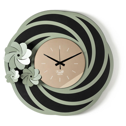 Orologio da parete Tahiti dal design floreale e tridimensionale, con una struttura traforata ispirata a petali stilizzati e tre fiori di diverse dimensioni. Il quadrante in vetro specchiato completa una composizione elegante. Vista frontale. Finitura nero/giada/bronzo