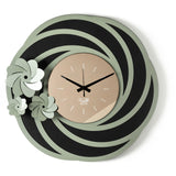 Orologio da parete Tahiti dal design floreale e tridimensionale, con una struttura traforata ispirata a petali stilizzati e tre fiori di diverse dimensioni. Il quadrante in vetro specchiato completa una composizione elegante. Vista frontale. Finitura nero/giada/bronzo