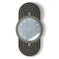 Orologio da parete Modus dal design verticale e contemporaneo, con struttura ovale traforata e quadrante in vetro specchiato impreziosito da indicatori a forma di rombo in cristallo acrilico. Un elegante equilibrio di geometrie e dettagli luminosi. Vista frontale. Finitura nero/fango/fumé.