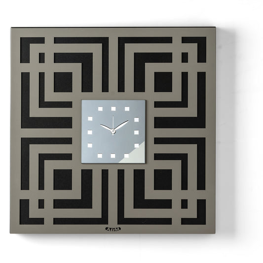 Orologio da parete Labyrinth dal design geometrico e tridimensionale, caratterizzato da un elegante motivo a labirinto traforato e da un quadrante quadrato in vetro specchiato. Indicatori in cristallo acrilico completano una composizione ricca di profondità e dettagli. Vista frontale, finitura nero/fango/fumé.