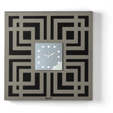 Orologio da parete Labyrinth dal design geometrico e tridimensionale, caratterizzato da un elegante motivo a labirinto traforato e da un quadrante quadrato in vetro specchiato. Indicatori in cristallo acrilico completano una composizione ricca di profondità e dettagli. Vista frontale, finitura nero/fango/fumé.